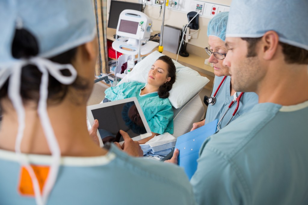 Nurses in a post-op unit discussing a patient's medical chart
